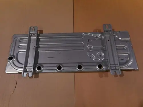 Sockel von Remeha, flaches, metallisches Bauteil mit mehreren Öffnungen und Montagehaltern, auf einem Karton nachgebildet.